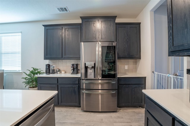 kitchen with tasteful backsplash, stainless steel appliances, and light hardwood / wood-style floors