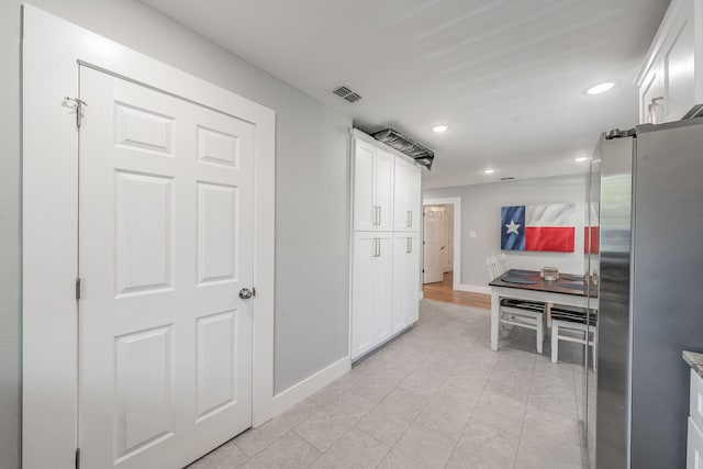 kitchen featuring light tile patterned floors, white cabinetry, and stainless steel fridge