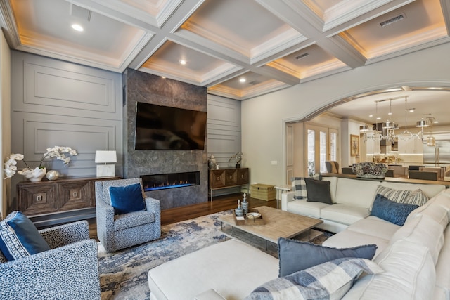 living room with beam ceiling, a high end fireplace, coffered ceiling, and ornamental molding