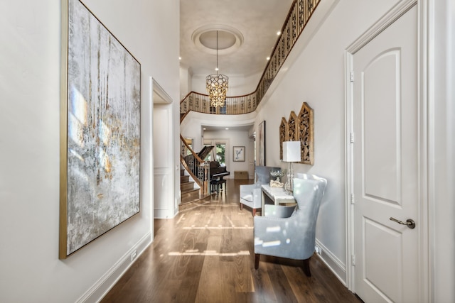 corridor featuring a chandelier, dark hardwood / wood-style floors, and a towering ceiling