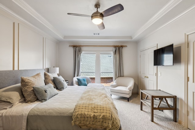 bedroom with ceiling fan, light carpet, a tray ceiling, and ornamental molding