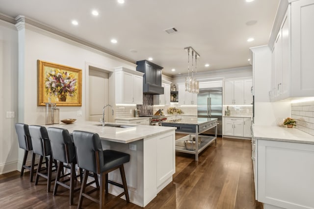 kitchen featuring kitchen peninsula, sink, high end appliances, white cabinetry, and hanging light fixtures