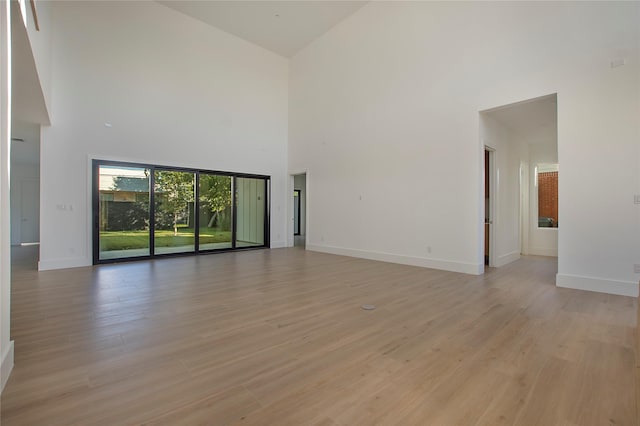 unfurnished living room featuring high vaulted ceiling and light hardwood / wood-style flooring