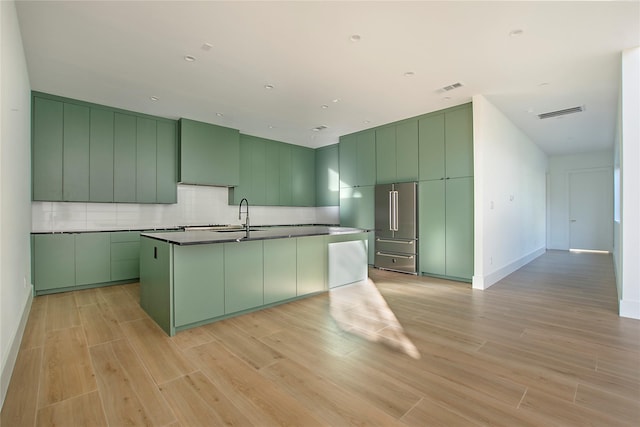 kitchen with green cabinets, sink, backsplash, and high end fridge