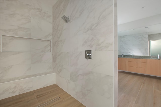 bathroom featuring tiled shower and vanity