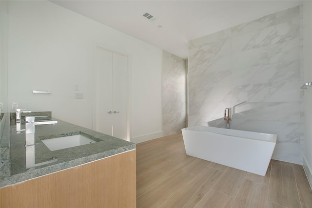 bathroom featuring a bathing tub, tile walls, hardwood / wood-style flooring, and vanity