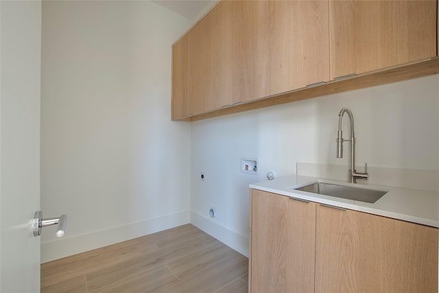 clothes washing area featuring cabinets, electric dryer hookup, sink, hookup for a washing machine, and light hardwood / wood-style flooring