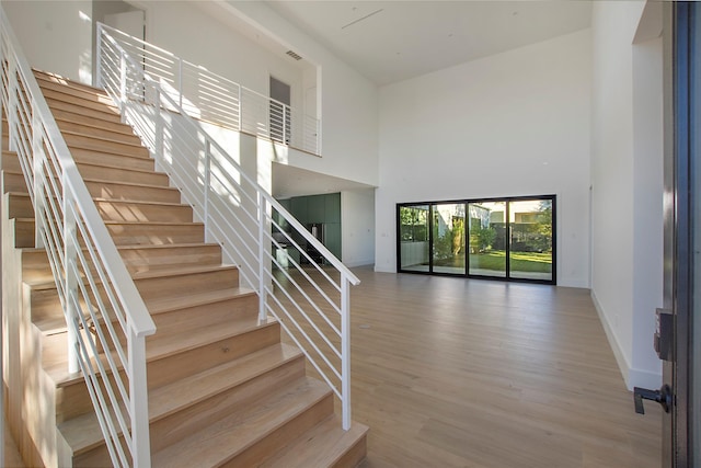 stairway with a towering ceiling and hardwood / wood-style floors