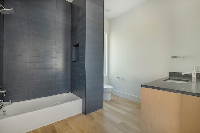 full bathroom featuring toilet, tiled shower / bath, hardwood / wood-style flooring, and vanity