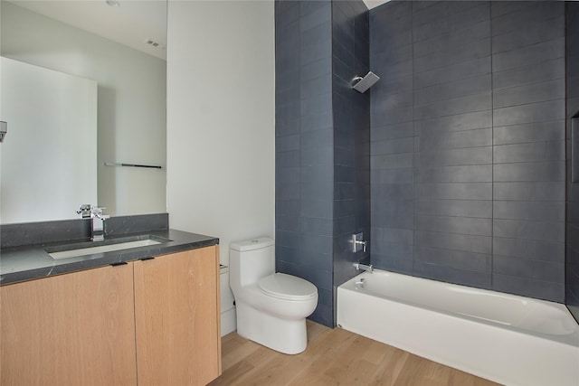 full bathroom featuring toilet, tiled shower / bath, hardwood / wood-style flooring, and vanity