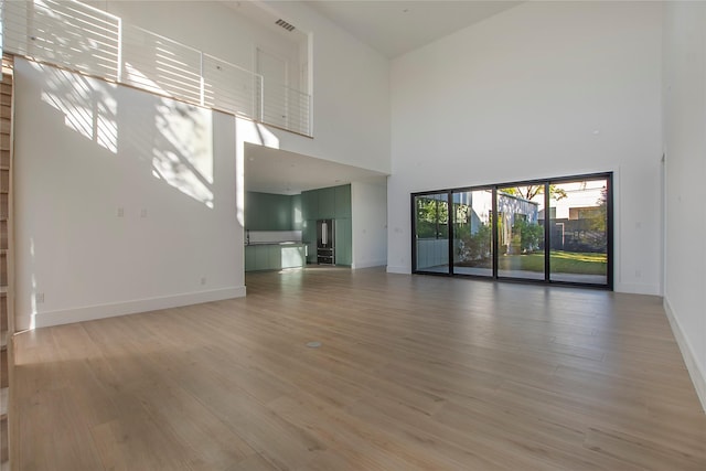 unfurnished living room with wood-type flooring and a high ceiling