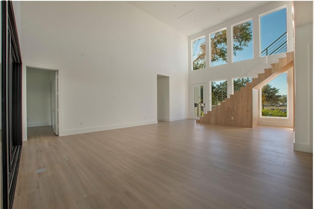 unfurnished living room with a high ceiling and light wood-type flooring