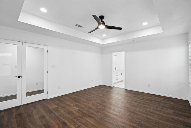 spare room with ceiling fan, dark wood-type flooring, and a raised ceiling