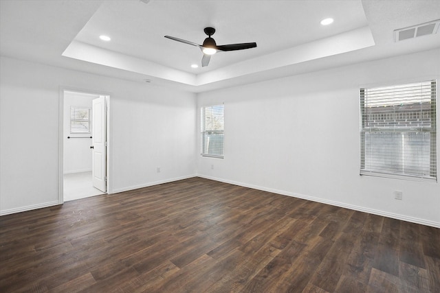 empty room featuring ceiling fan, dark hardwood / wood-style floors, and a tray ceiling