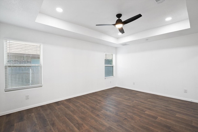 unfurnished room featuring dark wood-type flooring, a tray ceiling, and ceiling fan