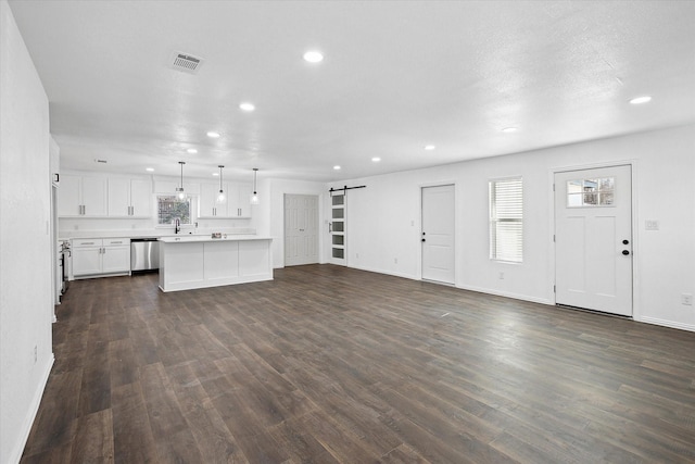 unfurnished living room with dark wood-type flooring, a barn door, and sink