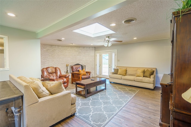 living room featuring a skylight, french doors, a textured ceiling, and light hardwood / wood-style floors