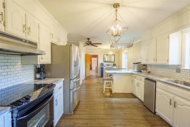 kitchen featuring a breakfast bar area, appliances with stainless steel finishes, tasteful backsplash, pendant lighting, and white cabinets