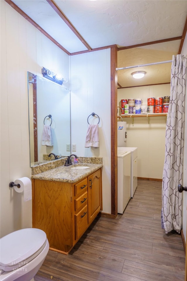 bathroom with toilet, hardwood / wood-style floors, washing machine and clothes dryer, and vanity