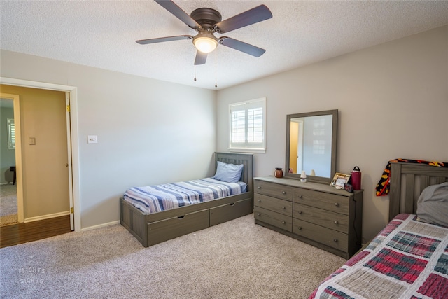 carpeted bedroom with ceiling fan and a textured ceiling