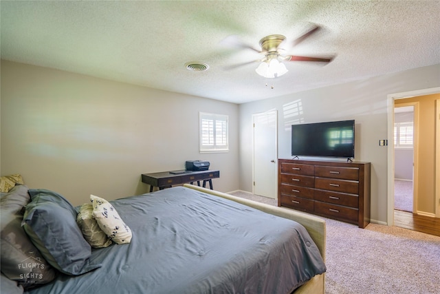 carpeted bedroom featuring a textured ceiling, ceiling fan, and multiple windows