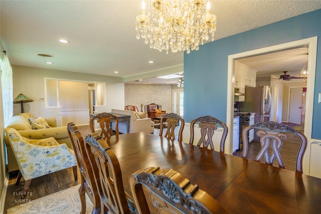 dining area with wood-type flooring, ceiling fan with notable chandelier, and a textured ceiling