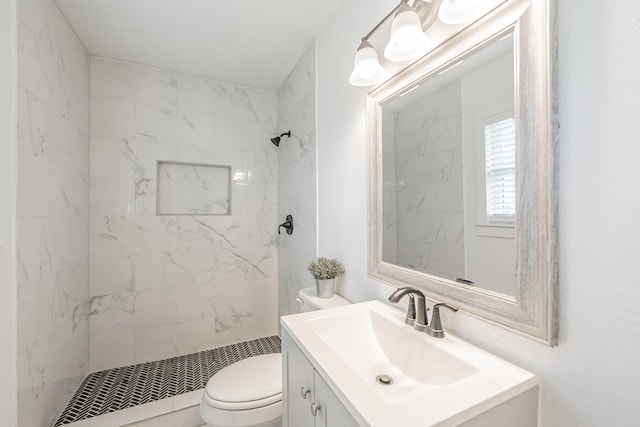 bathroom with toilet, vanity, and a tile shower