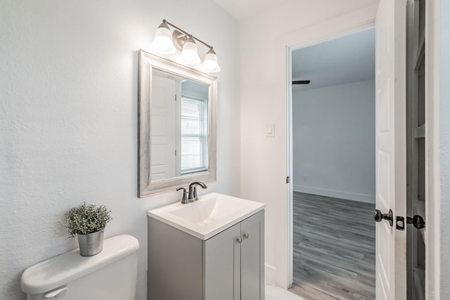 bathroom with toilet, wood-type flooring, and vanity