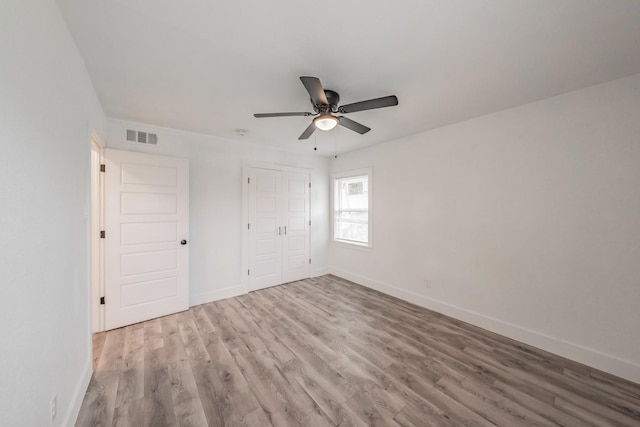 unfurnished bedroom featuring ceiling fan, a closet, and light wood-type flooring