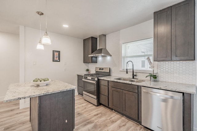 kitchen featuring decorative light fixtures, sink, dark brown cabinetry, appliances with stainless steel finishes, and wall chimney exhaust hood