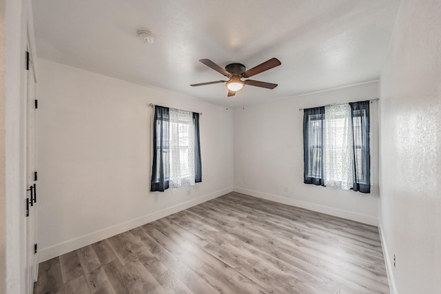 spare room featuring ceiling fan, light wood-type flooring, and a healthy amount of sunlight