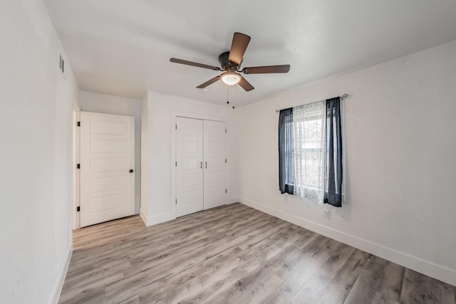 unfurnished bedroom featuring light wood-type flooring, ceiling fan, and a closet