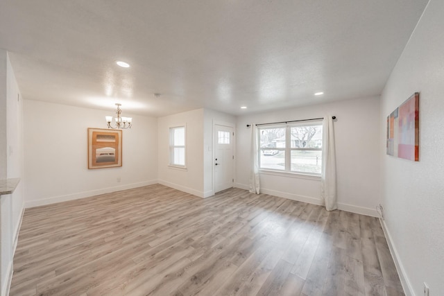 unfurnished living room with light hardwood / wood-style flooring and an inviting chandelier