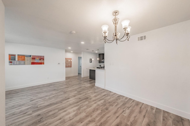 unfurnished living room with a notable chandelier and light wood-type flooring