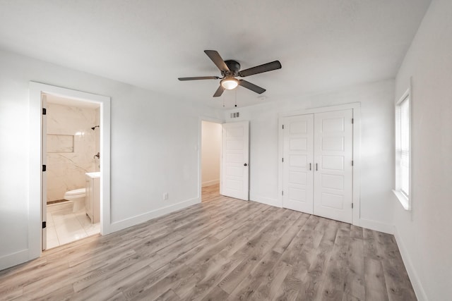 unfurnished bedroom with ceiling fan, a closet, light hardwood / wood-style floors, and ensuite bath