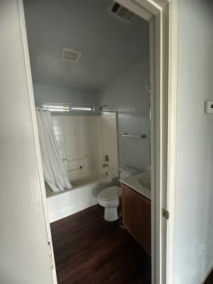 full bathroom with toilet, hardwood / wood-style floors, vanity, and shower / tub combo with curtain