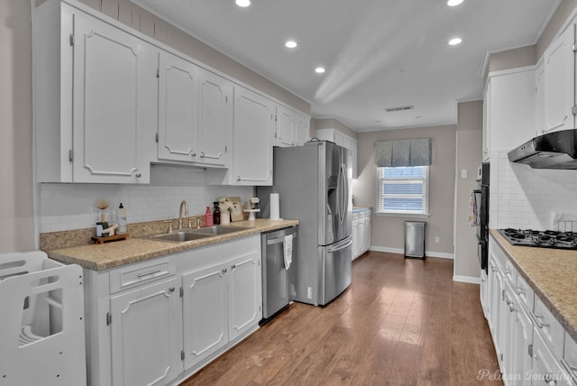 kitchen with stainless steel appliances, range hood, crown molding, white cabinets, and sink