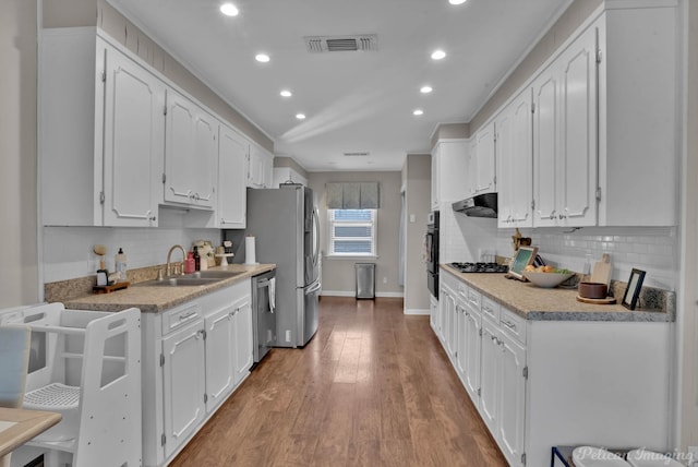 kitchen featuring tasteful backsplash, white cabinets, sink, and stainless steel appliances