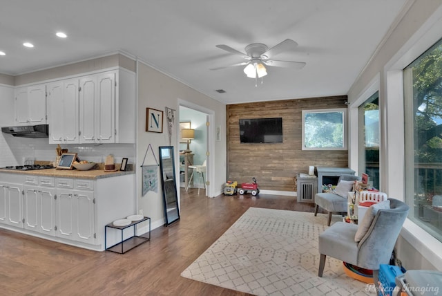 kitchen with ceiling fan, white cabinetry, stainless steel gas cooktop, light wood-type flooring, and ornamental molding