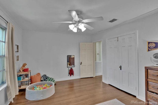 playroom with light wood-type flooring, ceiling fan, and ornamental molding