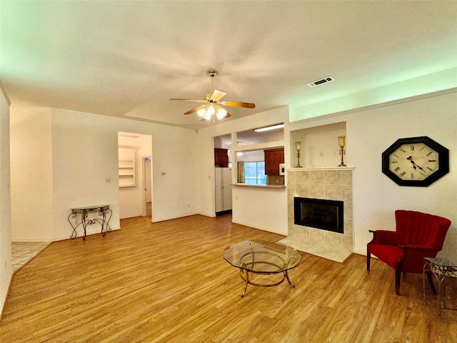 living room with ceiling fan, light hardwood / wood-style floors, and a fireplace