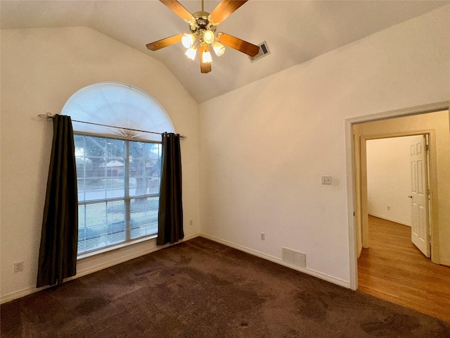 carpeted spare room featuring ceiling fan and vaulted ceiling