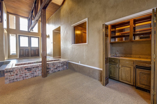 carpeted entryway with high vaulted ceiling, beamed ceiling, sink, wooden ceiling, and french doors