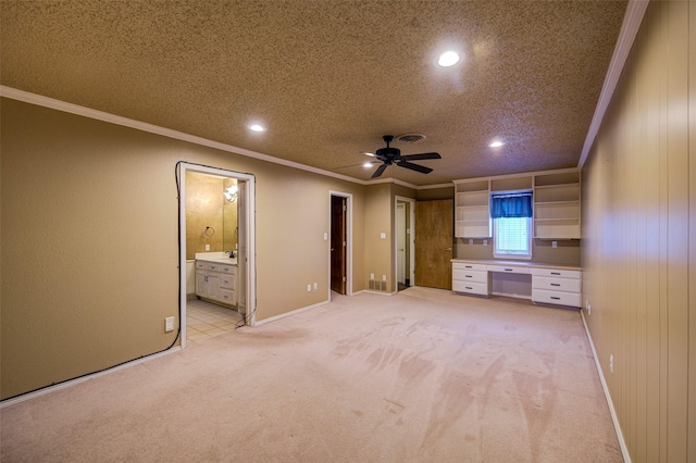 unfurnished living room featuring wood walls, light carpet, a textured ceiling, ornamental molding, and ceiling fan