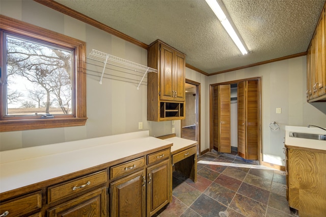 kitchen featuring crown molding, built in desk, sink, and a textured ceiling