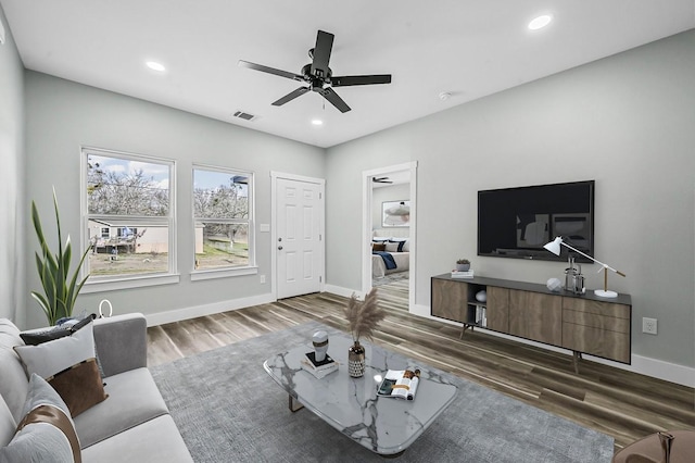 living room featuring ceiling fan and dark hardwood / wood-style flooring