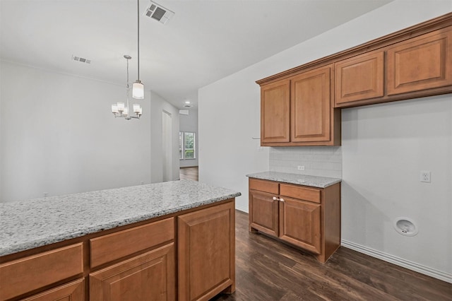 kitchen with decorative light fixtures, light stone countertops, backsplash, and dark wood-type flooring