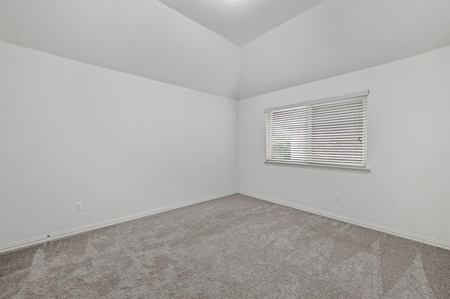 spare room with light colored carpet and vaulted ceiling