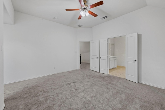 unfurnished bedroom featuring ceiling fan, light carpet, vaulted ceiling, and connected bathroom