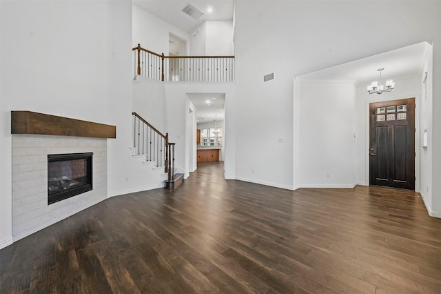 unfurnished living room with a chandelier, crown molding, a towering ceiling, and dark hardwood / wood-style flooring